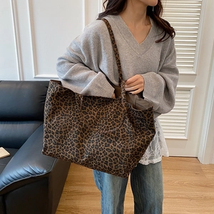 Large leopard print tote bag with double handles shown on a model in a minimalist room