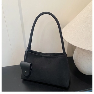 Détail de la texture en daim mat et du charme noué sur ce sac à main minimaliste noir