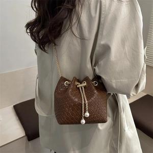 Vintage brown woven bucket bag with elegant pearl chain and thin gold shoulder strap