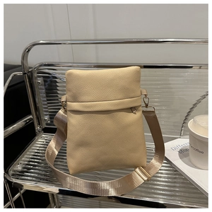 Detail of beige lychee grain leather crossbody bag with adjustable nylon strap and gold hardware