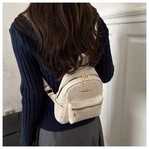 Détail d'un mini sac à dos crème chic avec motif crocodile et fermetures dorées élégantes