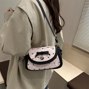 Pink crossbody bag with black bow prints and heart pendant in a stylish autumn scene