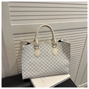 Close-up of M-pattern printed tote bag with beige leather trim and golden hardware