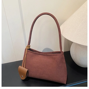Détail de la texture velours côtelé marron et petit pendentif en cuir sur le sac porté