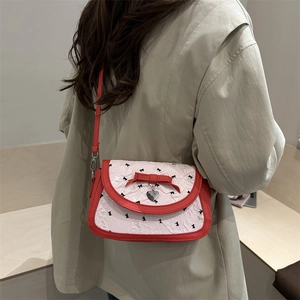 Retro red and white crossbody bag with bow patterns shown on model shoulder