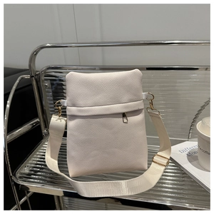 Detail of cream lychee leather square bag with gold zipper and wide fabric strap