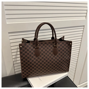 Close-up of large brown monogram tote bag with gold hardware and M-pattern detailing