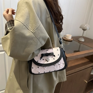 Chic pink pleated crossbody bag with black bow print and heart charm shown on a model