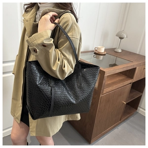 Gros plan d'un sac cabas noir tissé porté par un mannequin avec un trench-coat beige chic