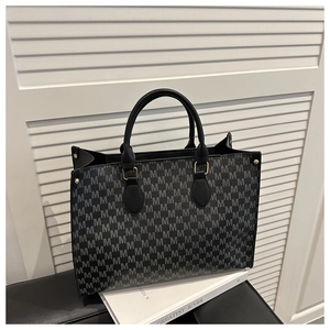 Detailed view of women's tote bag with M-pattern monogram and gold-tone hardware
