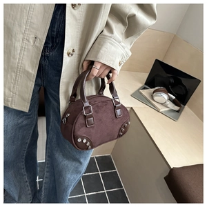 Detail of retro dark brown suede handbag with silver studs on urban casual background
