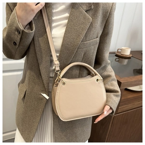Detail of elegant beige semi-circular handbag with gold D-rings and adjustable strap