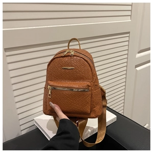 Détail de la texture tressée marron et de la fermeture éclair dorée du mini sac à dos