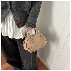 Detail of khaki suede shell bag with silver rivets and vintage top handle design