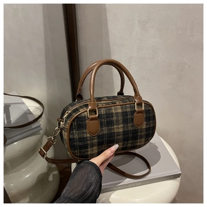 Detail of vintage brown plaid pillow bag with premium leather handles and gold zippers