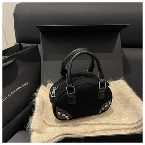 Detail of black suede bowling bag with silver rivets and sleek leather handles