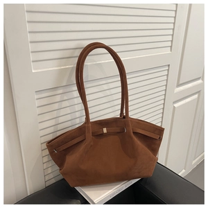 Close-up of brown suede tote bag featuring slim straps and gold decorative buckle