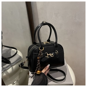 Detail of black leather Boston bag featuring gold horsebit accent and tassel charm