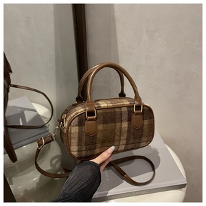 Macro detail of retro plaid woolen Boston bag with leather straps and gold hardware