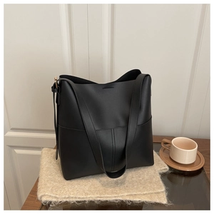 Detail of minimalist black PU leather tote with vertical stitching and gold buckle