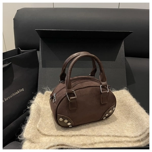 Close-up of brown suede mini Boston bag with silver rivets on beige textured fabric