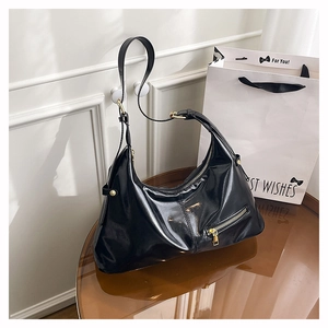 Detail der glänzenden schwarzen Hobo-Tasche mit Lackoberfläche und goldener Reißverschluss