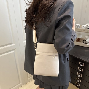 Minimalist beige pebble leather crossbody bag with adjustable strap worn by model