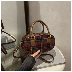 Detail of red and green plaid woolen fabric with premium brown leather strap and gold zipper