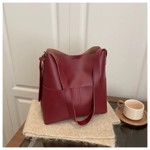 Detail of burgundy leather tote bag with vertical stitching on a cozy beige knit mat