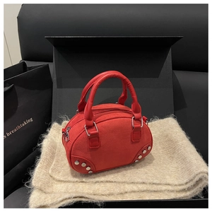 Detail of red suede semi-circle handbag featuring silver rivets and metal zipper