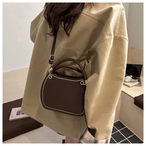 Detail of dark brown semi-circle handbag with white contrast stitching and gold hardware