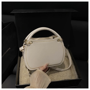 Detailed view of white leather crossbody bag in luxury black gift box with gold stitching