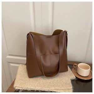 Macro detail of brown leather tote bag with vertical stitching and coffee cup background