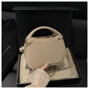Detailed view of beige leather crossbody bag with gold hardware in a premium gift box