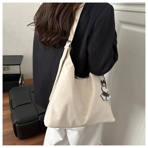 Detail of a large cream tote bag with adjustable strap and cute puppy pendant