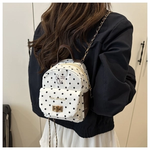 Close-up of mini polka dot canvas backpack with brown leather details and chain strap