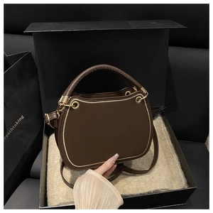 Detail of dark brown cat-head square bag with gold metal trim and thick handle in gift box