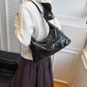 Schicke Hobo-Tasche aus schwarzem Lackleder mit goldenen Details am Model
