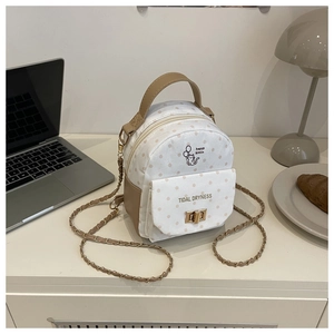 Close-up of mini backpack with kitten prints, gold chain strap, and metal twist lock