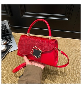 Close-up of a red crocodile pattern handbag with gold clasp in a stylish office setting