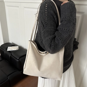 Minimalist off-white large capacity tote bag shown on model with chic black and white outfit