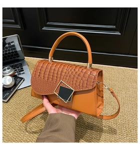 Detail of caramel brown crossbody bag with crocodile embossing and golden buckles