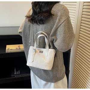 Gros plan d'un sac seau en cuir verni blanc avec fermoir argenté porté par un mannequin