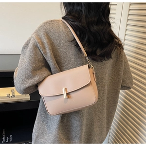 Detail view of stylish beige leather underarm bag with gold cylindrical metal clasp