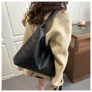 Detail view of large black hobo tote bag with lychee texture shown on shoulder