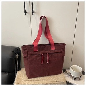 Close-up of leopard embossed burgundy tote bag with woven zippers and red fabric handles