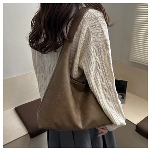 Brown leather shoulder tote bag detail showing pleated texture and stitching