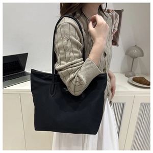 Close-up of black nylon tote bag featuring YIDALON logo and rope handle on a model