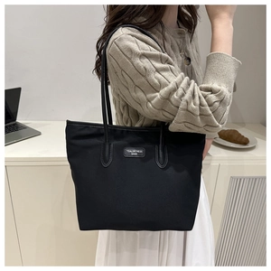Chic black tote bag with brand patch shown in a modern lifestyle commute setting