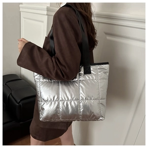 Side view of silver quilted tote bag with black strap and metallic gloss finish